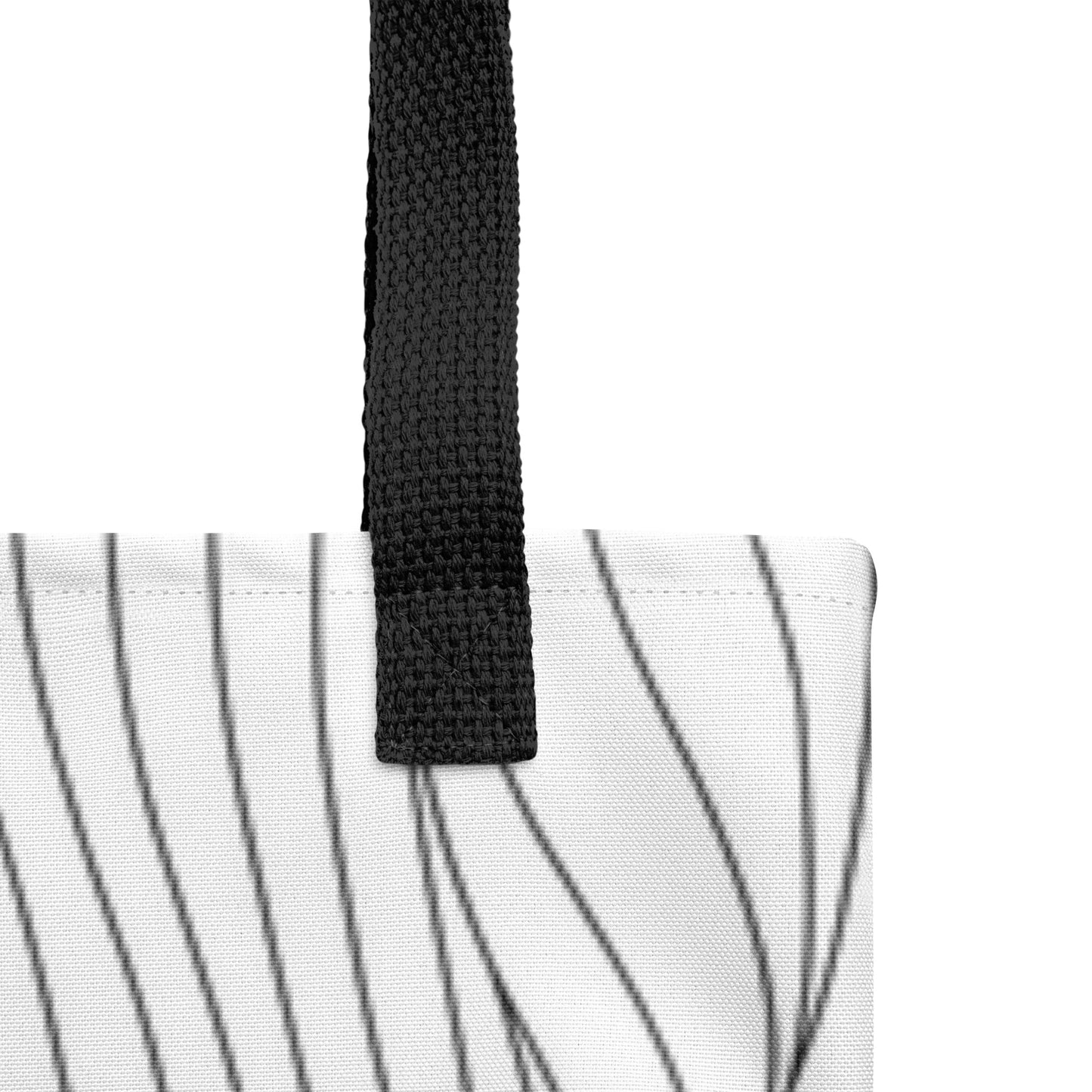 Close-up of the white tote fabric and black strap, highlighting the stitching, textured canvas, and black curved line pattern.