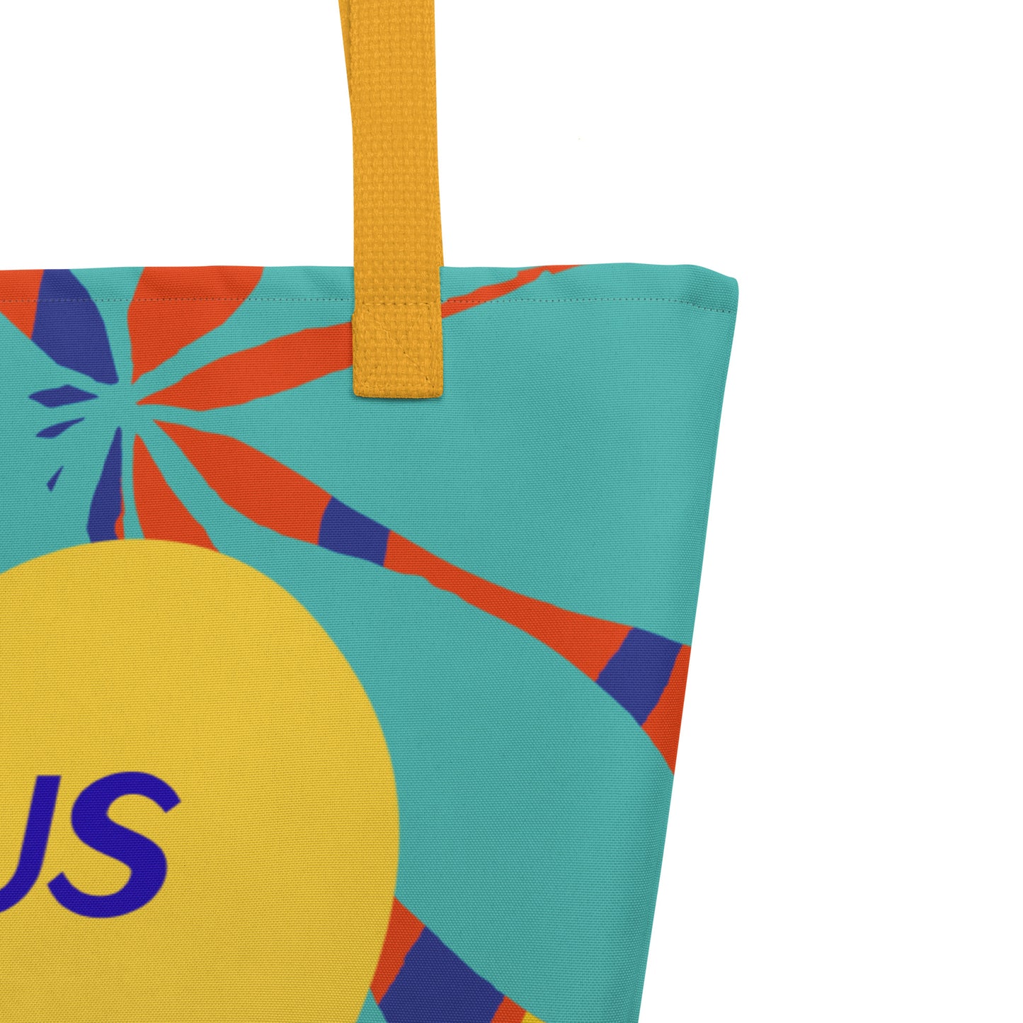 Close-up of the tote’s upper corner showing a mustard-yellow woven strap stitched to the top edge, with a teal background and orange-and-navy leaf/palm shapes; the edge of a large yellow heart and part of the blue “JESUS” lettering are visible at the lower left.