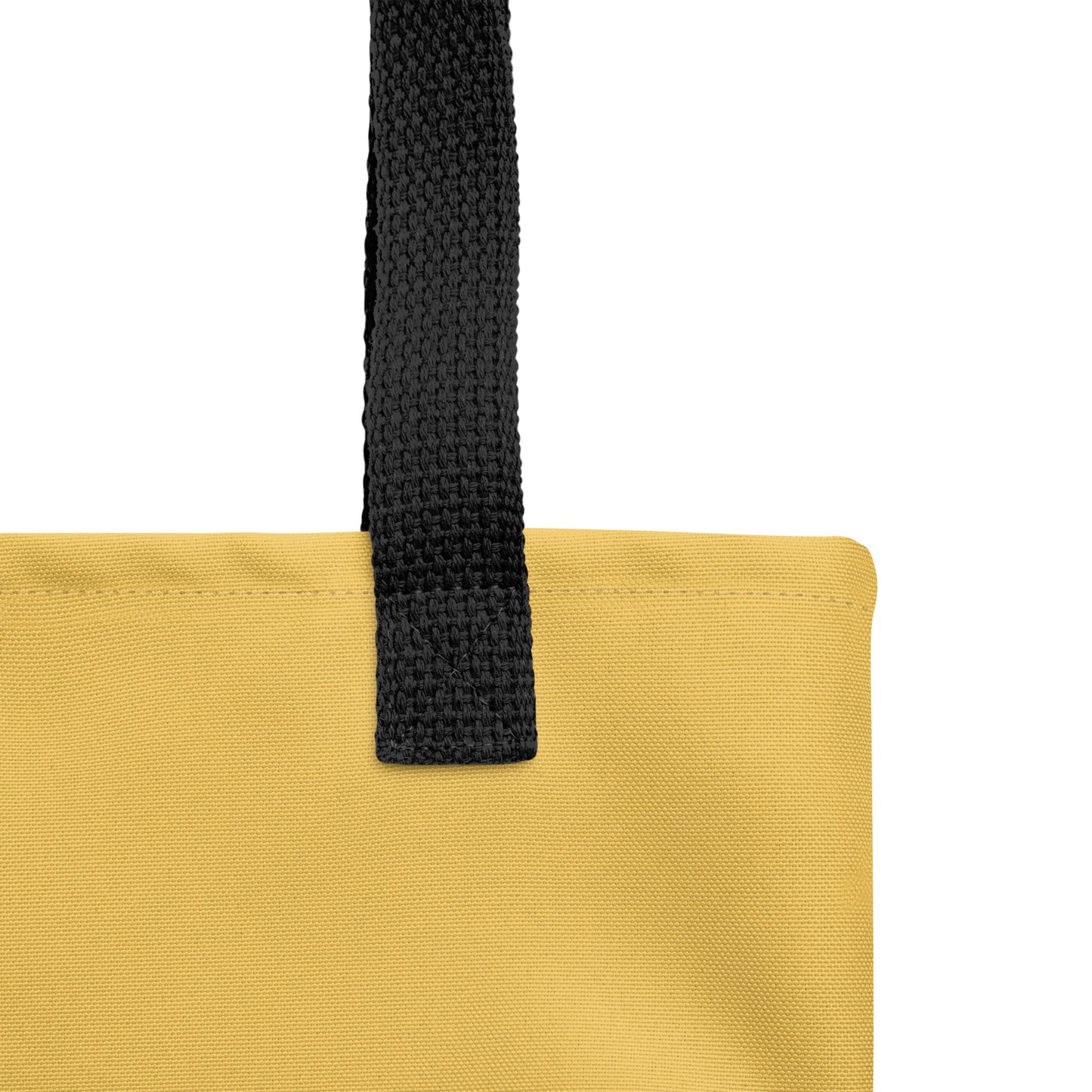 Close-up of black woven handle and stitched top edge on the tote bag’s yellow fabric.