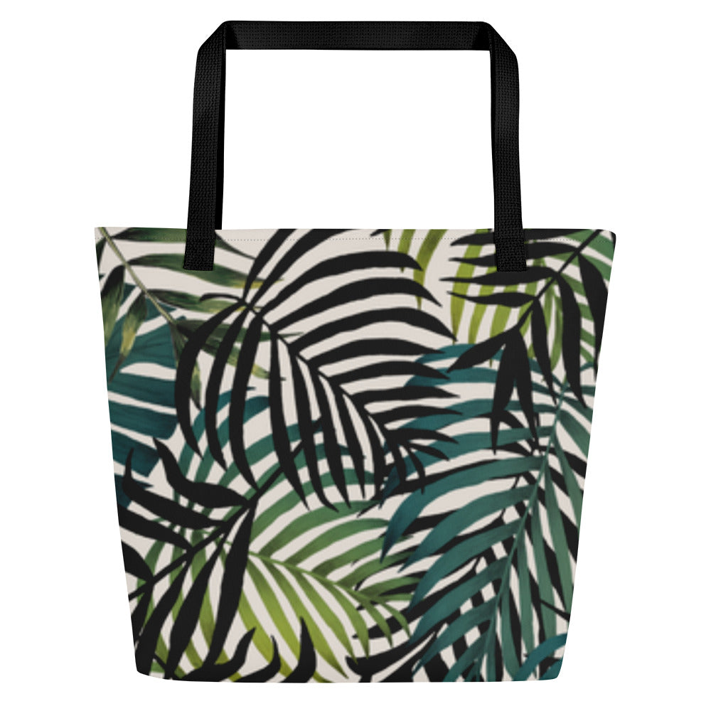 Back view of tote bag with an all-over tropical leaf pattern in shades of green and dark tones, with black straps.