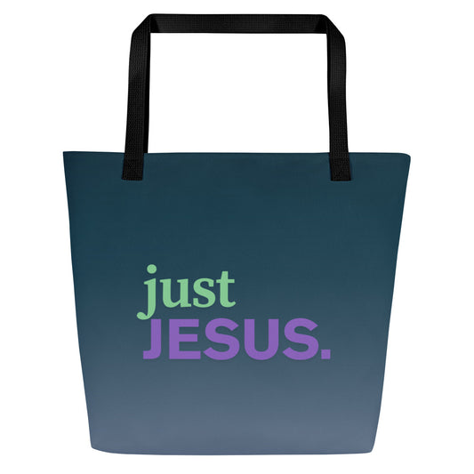 Front view of dark teal tote bag with black straps and the phrase “just JESUS.” in green and purple lettering.
