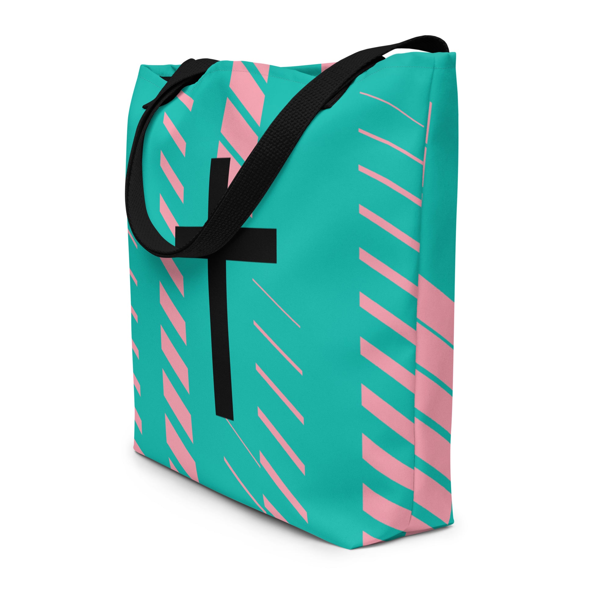 Angled view of teal tote bag with black straps, pink diagonal stripe accents, and a large black cross on the front.