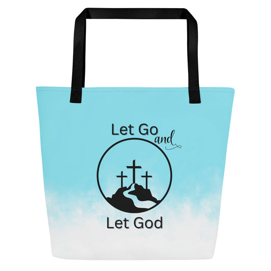 Front view of tote bag with black straps, light blue-to-white ombré design, and “Let Go and Let God” graphic with three crosses in a circle.