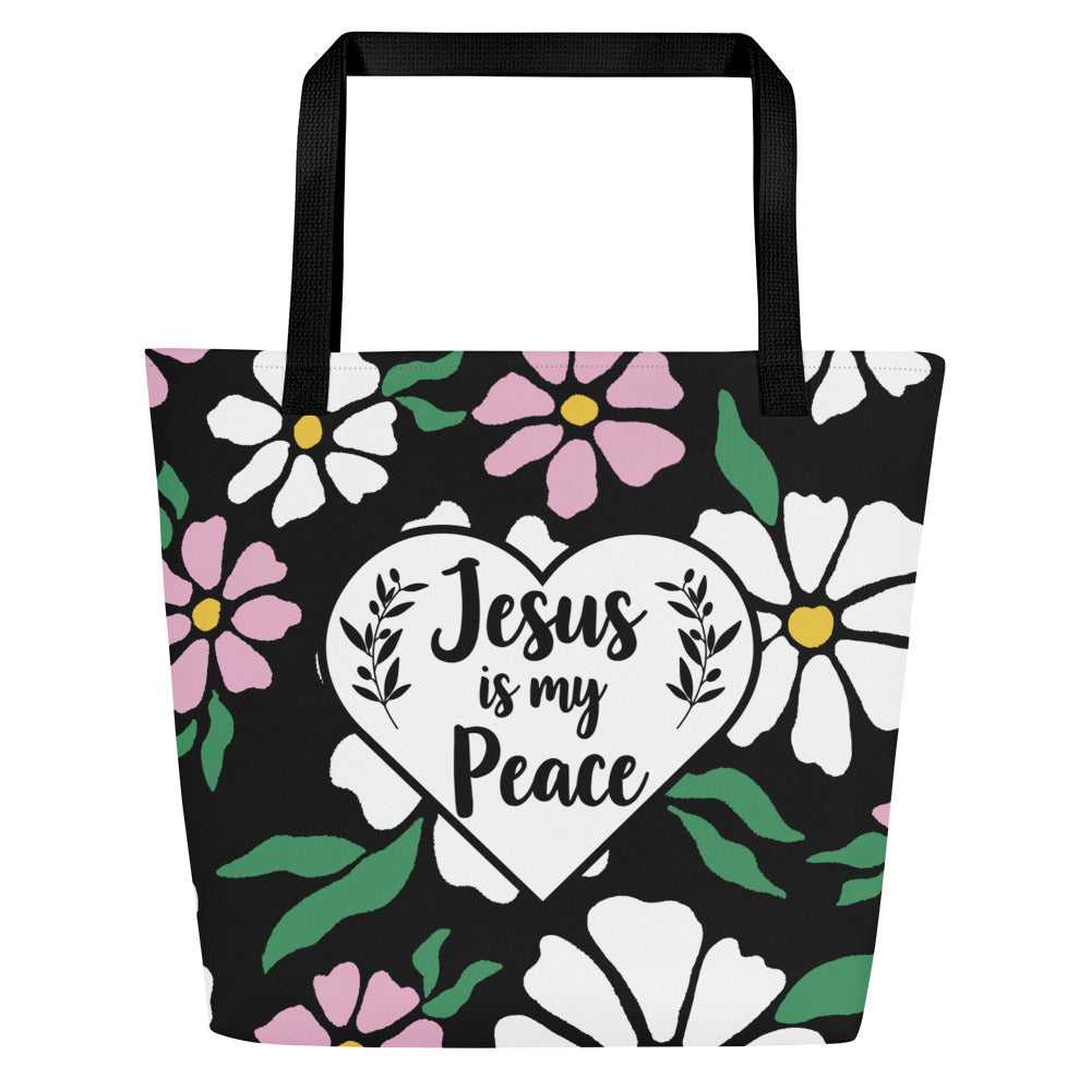 Front view of black tote bag with black straps, bold floral print, and a white heart graphic reading “Jesus is my Peace.”