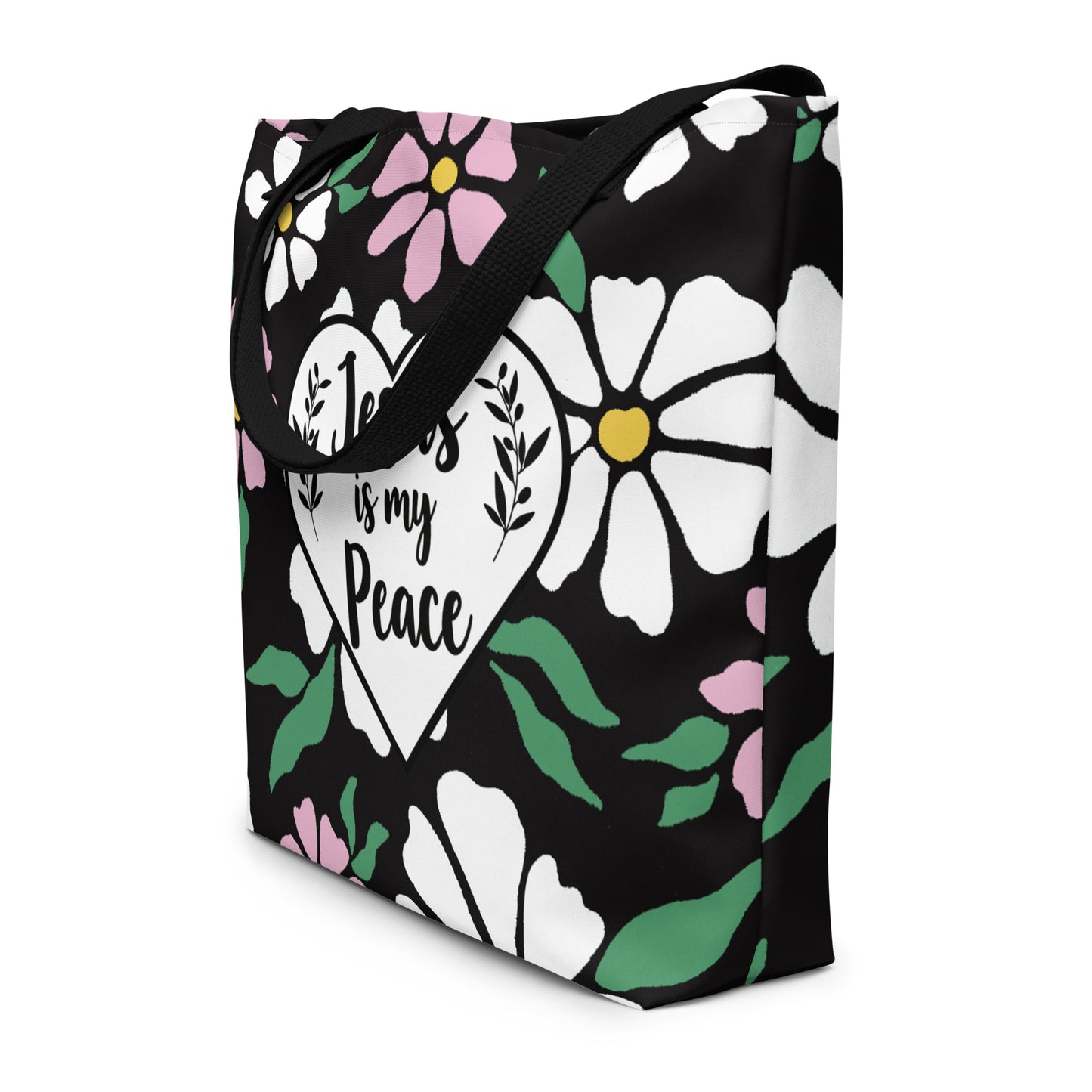 Angled view of black floral tote bag with black straps and “Jesus is my Peace” heart graphic.
