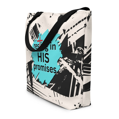 Angled view of white tote bag with black straps, abstract black pattern, and teal “resting in HIS promises” graphic.
