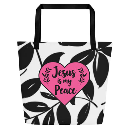 Front view of white tote bag with black straps, black leaf print, and a pink heart graphic reading “Jesus is my Peace.”