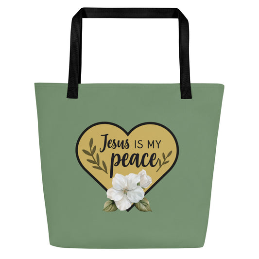 Front view of sage green tote bag with black straps featuring a gold heart graphic that reads “Jesus is my peace,” accented with leafy branches and a white flower illustration at the bottom of the heart.