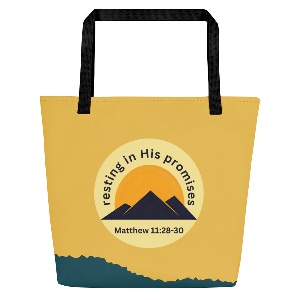 Front view of tote bag with black straps and a mustard-yellow upper section, a teal-blue band along the bottom, and a round emblem showing a golden sun behind navy mountains with the text “resting in His promises” and “Matthew 11:28–30.”