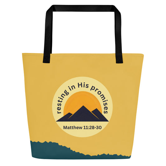 Front view of tote bag with black straps and a mustard-yellow upper section, a teal-blue band along the bottom, and a round emblem showing a golden sun behind navy mountains with the text “resting in His promises” and “Matthew 11:28–30.”