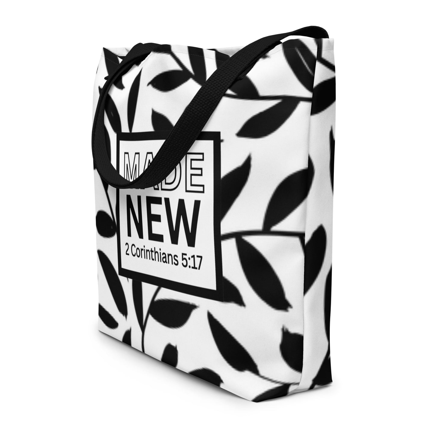 Angled view of black-and-white leaf print tote bag with black straps and “MADE NEW” (2 Corinthians 5:17)