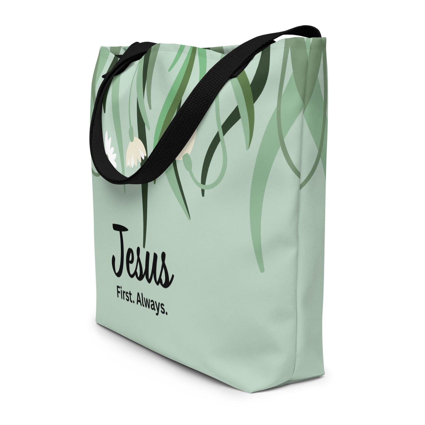 Angled view of sage green tote bag with black straps, leafy floral design, and “Jesus First. Always.” text.