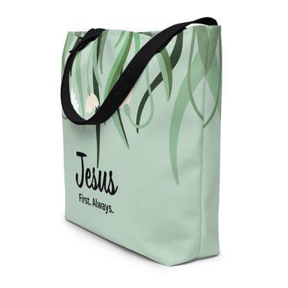 Angled view of sage green tote bag with black straps, leafy floral design, and “Jesus First. Always.” text.