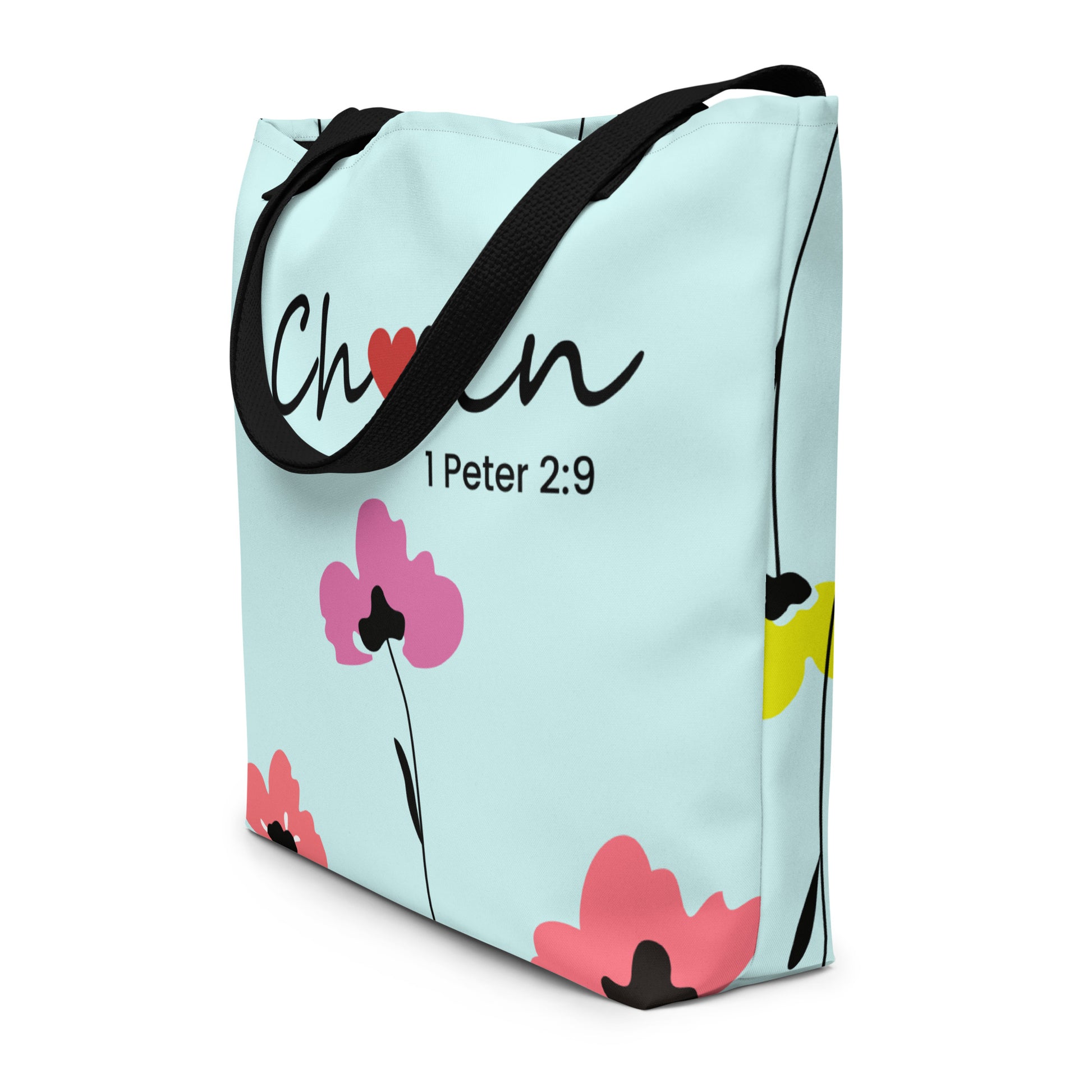 Angled side view of the tote showing the “Chosen” text wrapping slightly toward the edge and the floral pattern continuing around the side panel; black straps drape over the top.