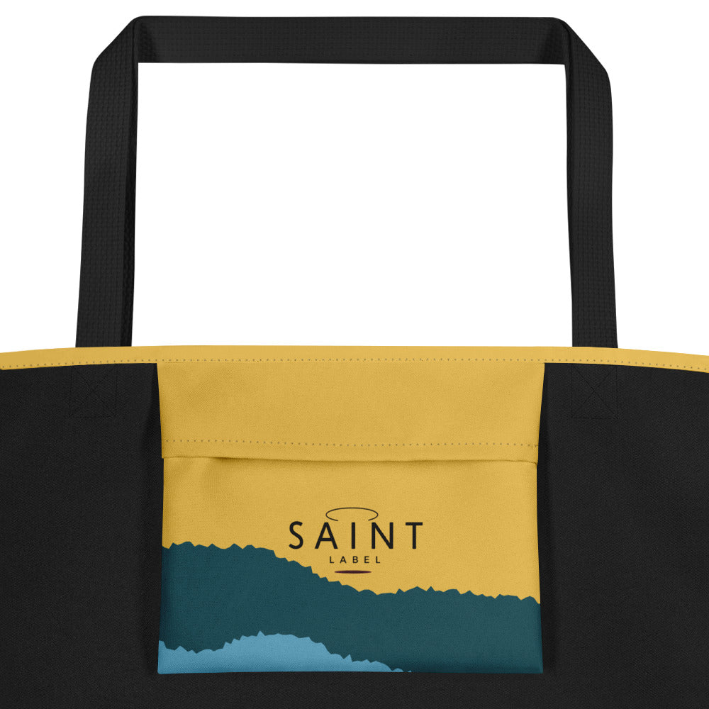 Inside pocket view showing a centered interior pocket labeled “Saint Label,” with black side panels and the mustard-yellow and teal-blue exterior colors visible above and below the pocket.