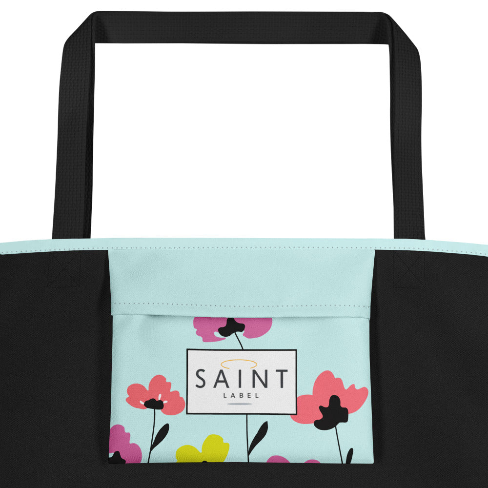 Inside pocket view showing black side panels and a pale aqua pocket panel printed with colorful flowers near the bottom. A centered white label reads “Saint Label."