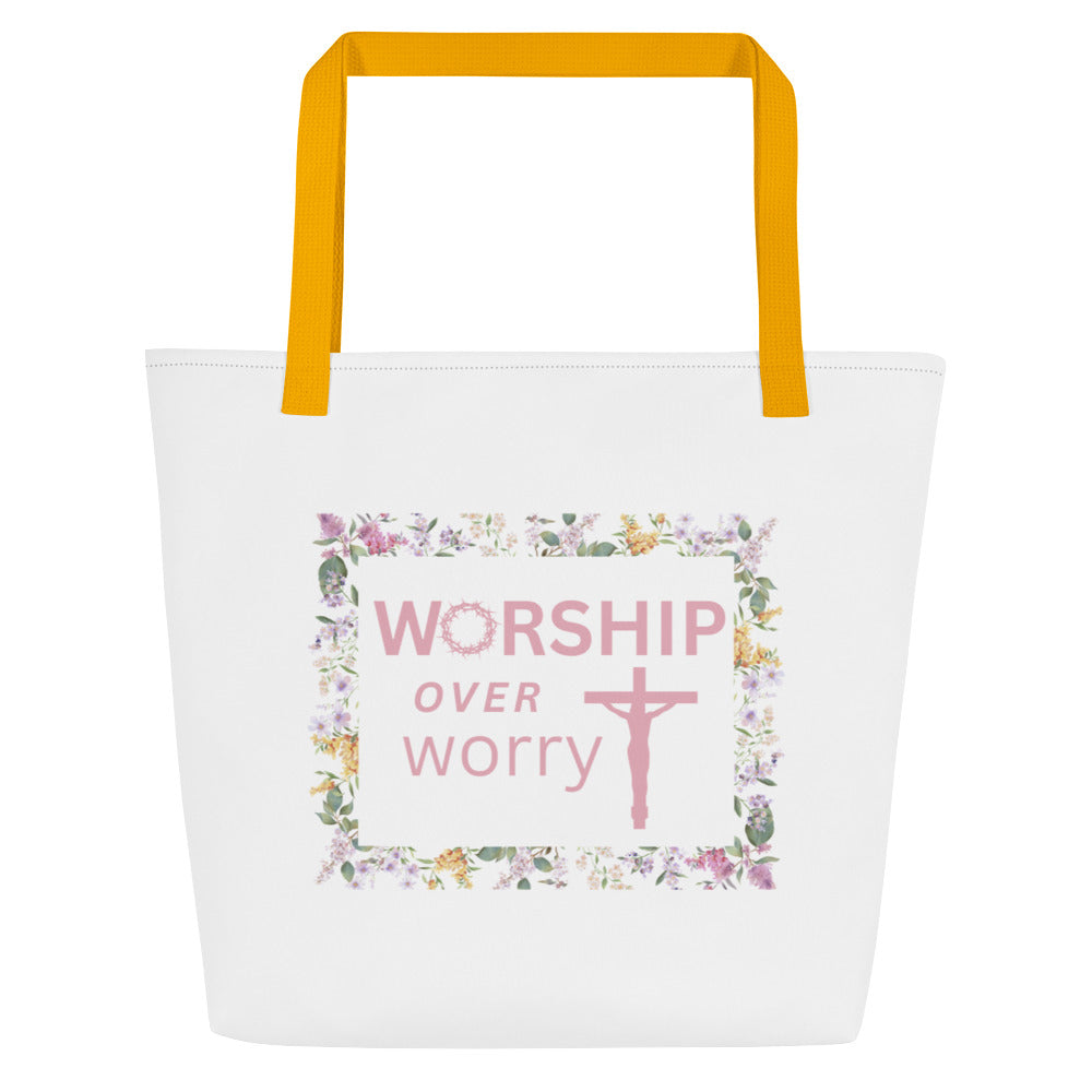 Front view of white tote bag with mustard yellow straps and a floral frame graphic reading “WORSHIP over worry” with a cross.