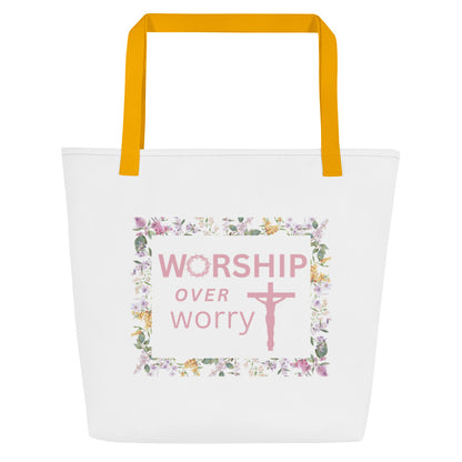 Front view of white tote bag with mustard yellow straps and a floral frame graphic reading “WORSHIP over worry” with a cross.