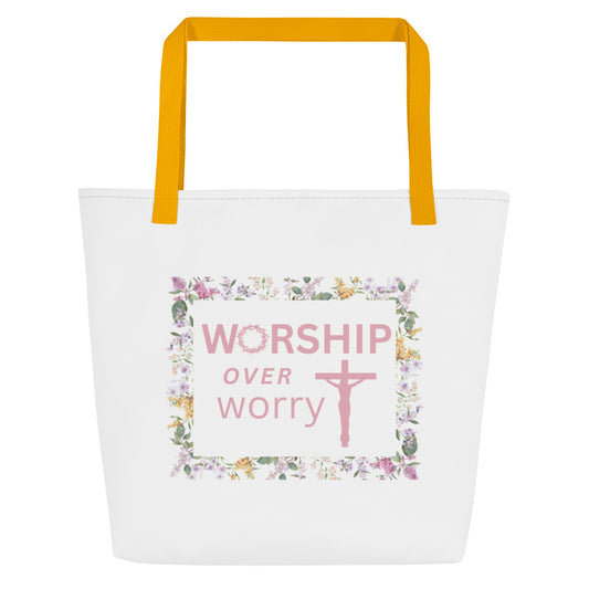 Front view of white tote bag with mustard yellow straps and a floral frame graphic reading “WORSHIP over worry” with a cross.
