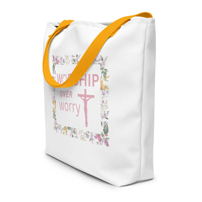Angled view of white tote bag with mustard yellow straps and “WORSHIP over worry” floral frame graphic with a cross.