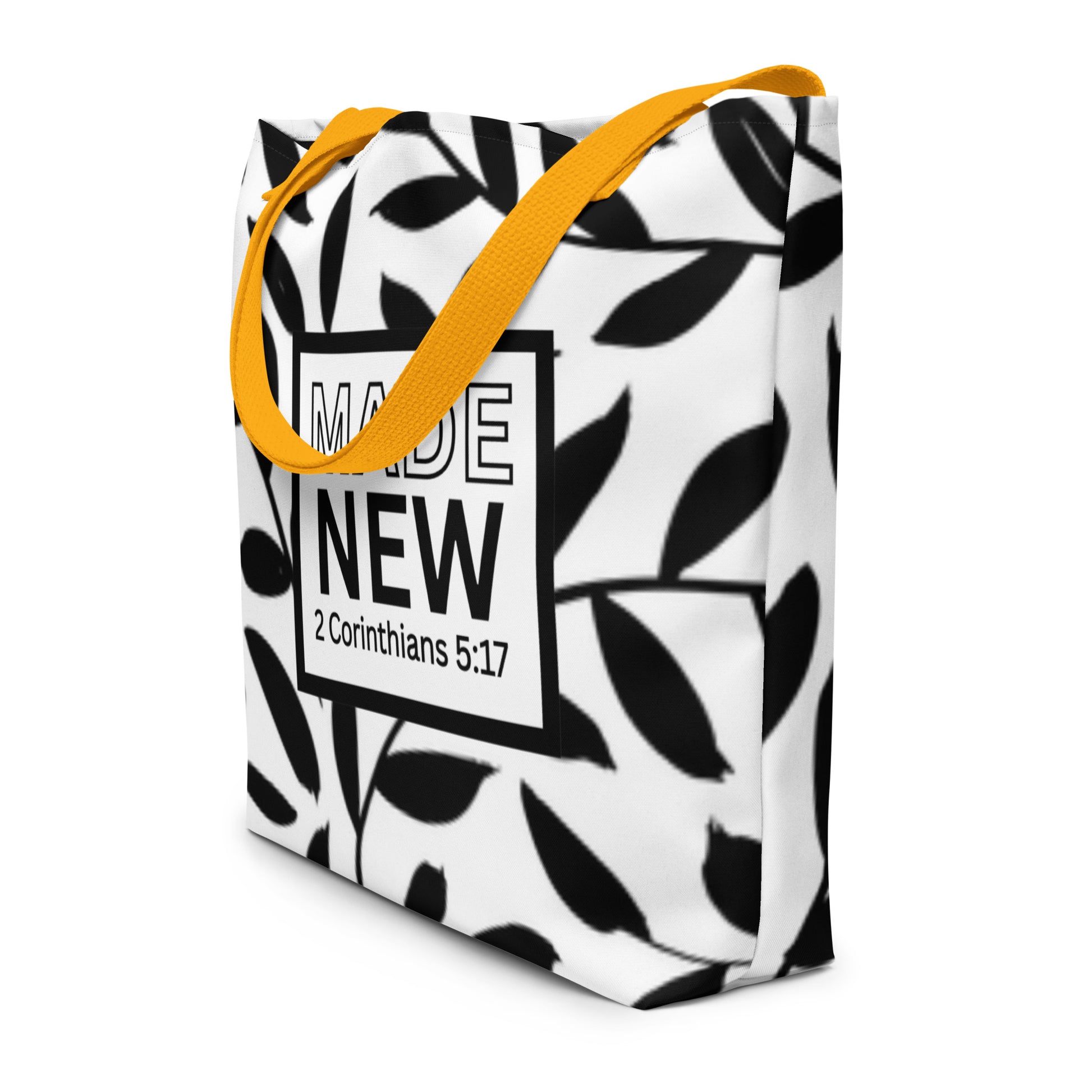 Angled view of black-and-white leaf print tote bag with yellow straps and “MADE NEW” (2 Corinthians 5:17)