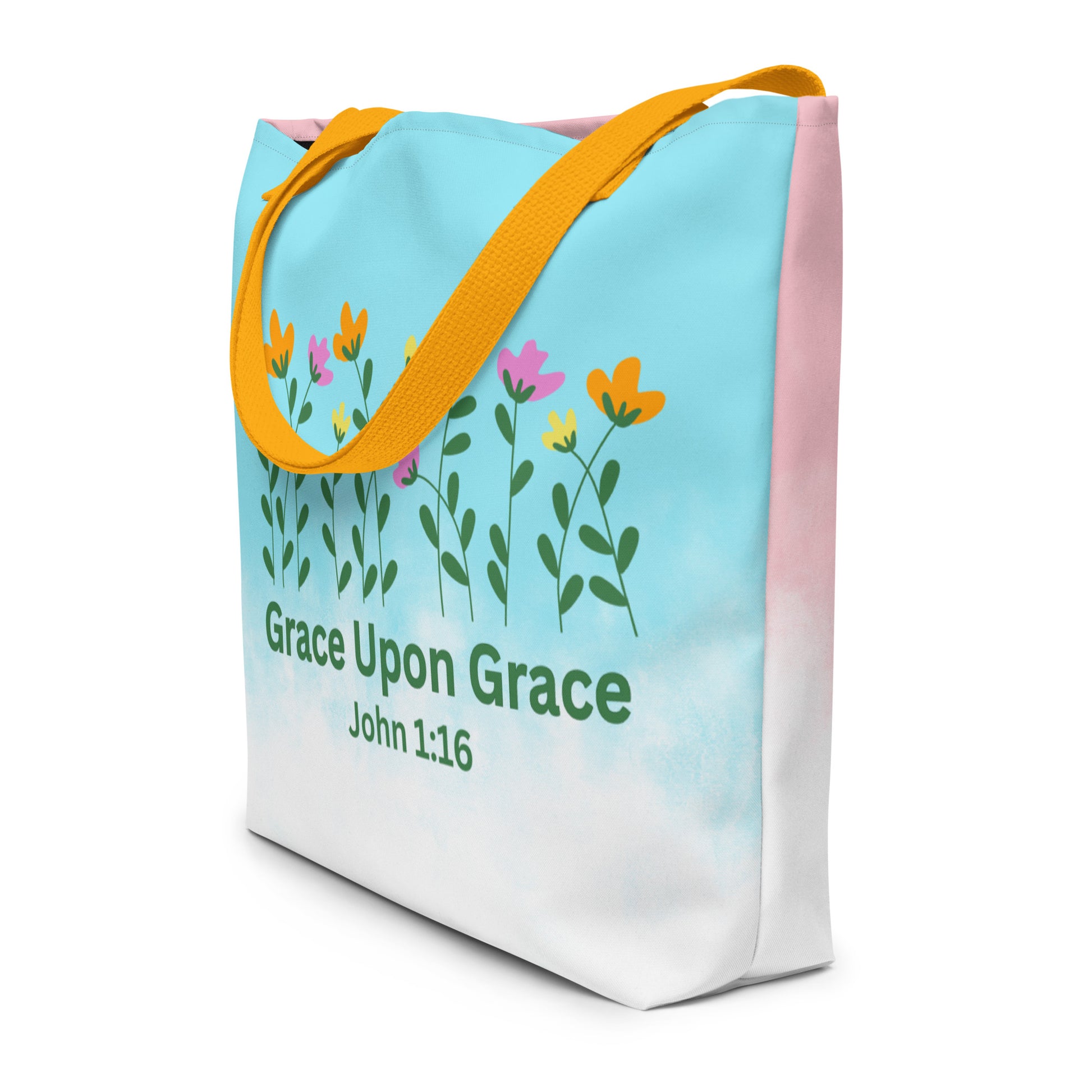 Angled view of the tote showing the blue-to-white front design wrapping slightly around the side panel, with the floral row and “Grace Upon Grace – John 1:16” text visible; yellow straps drape over the top edge.