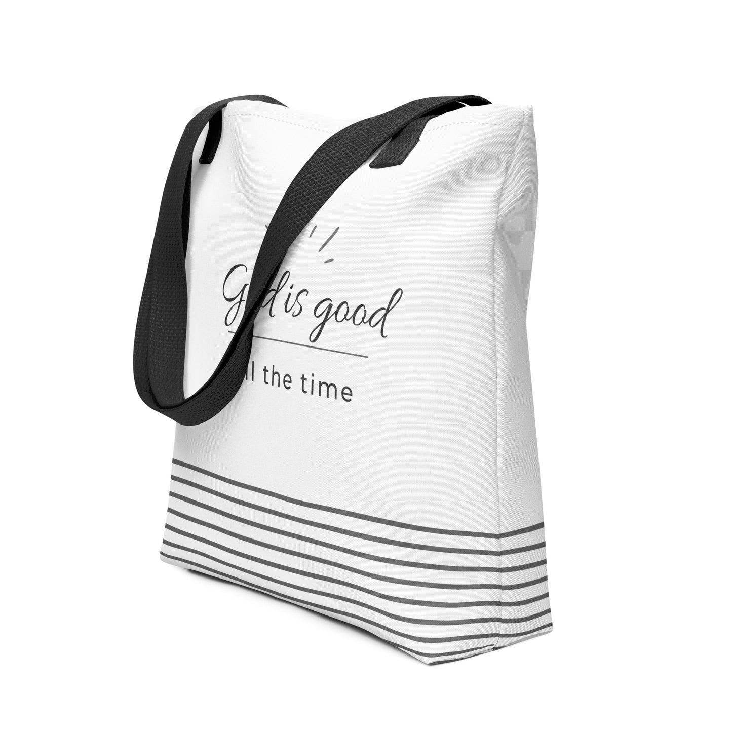 Angled view of a white tote bag with dark gray “God is good all the time” lettering and a gray striped base detail.