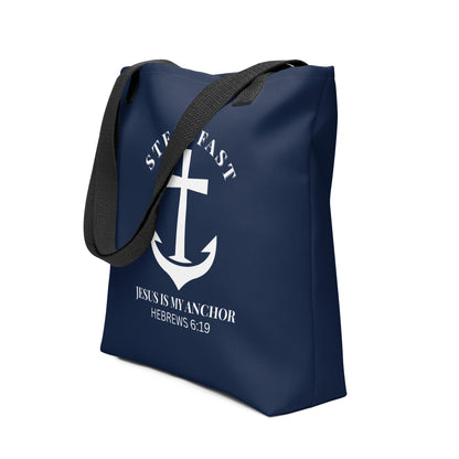 Angled view of the navy tote with black handles, showing the white anchor cross design with “STEADFAST” arched above and “JESUS IS MY ANCHOR” (Hebrews 6:19) underneath.