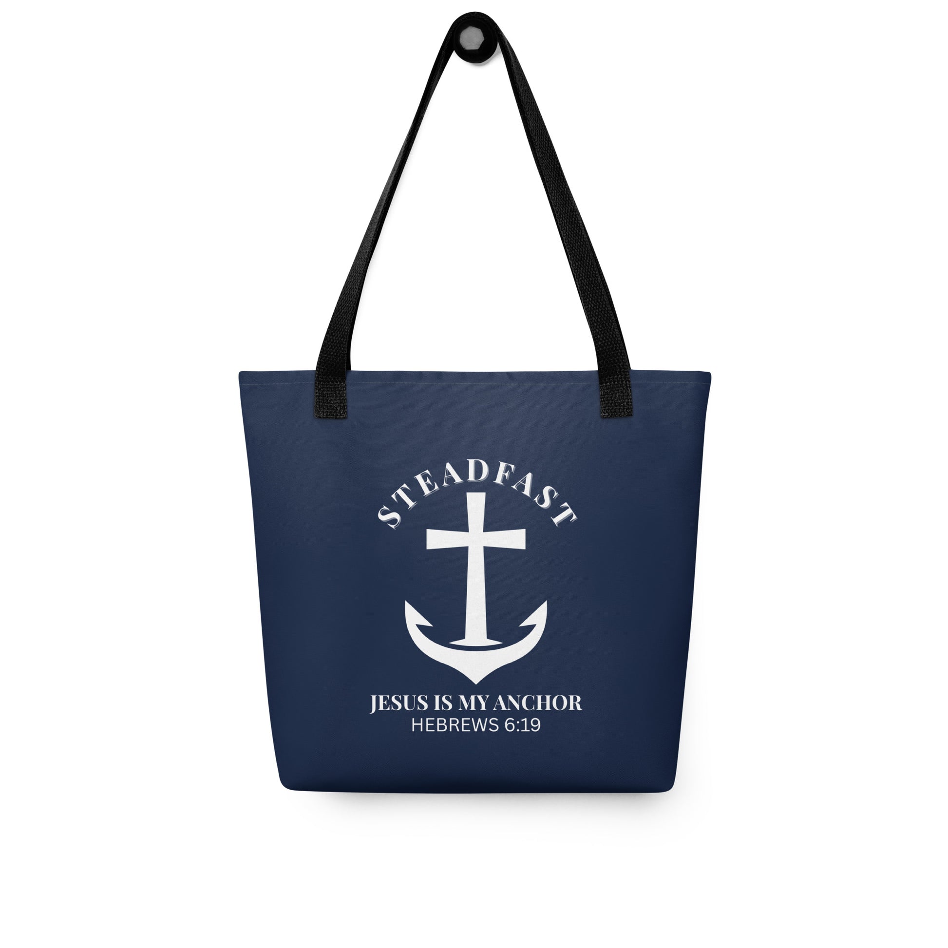 Navy blue tote bag with black straps hanging on a hook, displaying a white anchor-and-cross emblem with “STEADFAST” and “JESUS IS MY ANCHOR” (Hebrews 6:19).