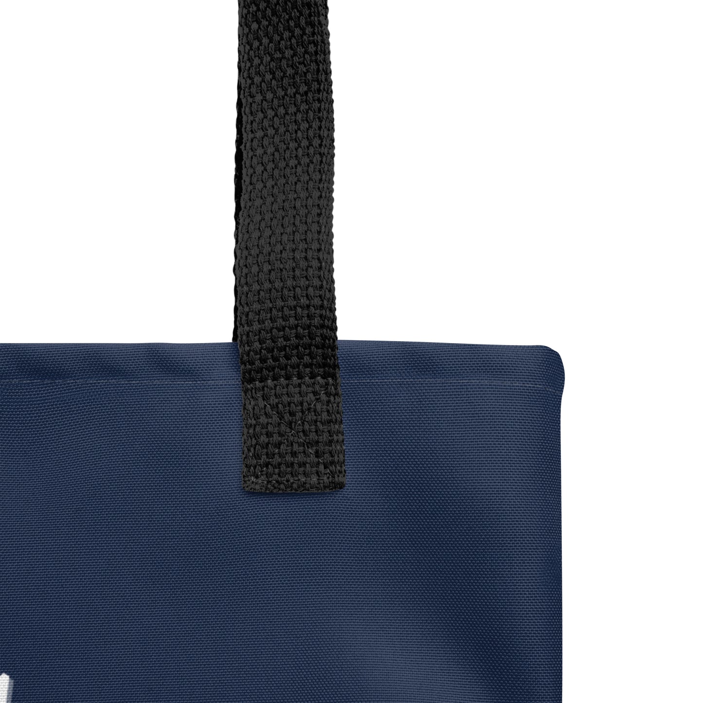 Close-up of the black handle attachment on the navy tote, showing the canvas texture and reinforced stitching.
