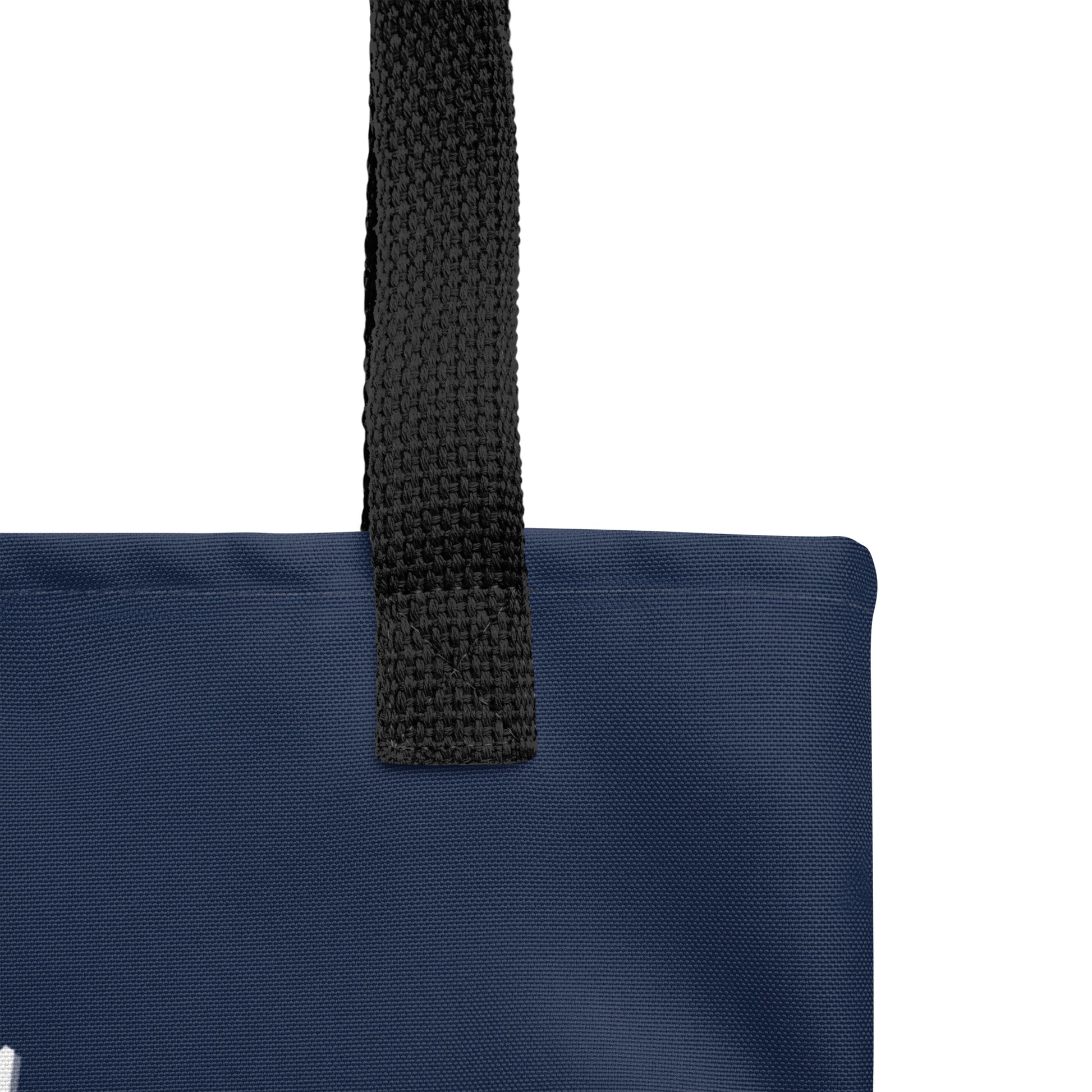 Close-up of the black handle attachment on the navy tote, showing the canvas texture and reinforced stitching.