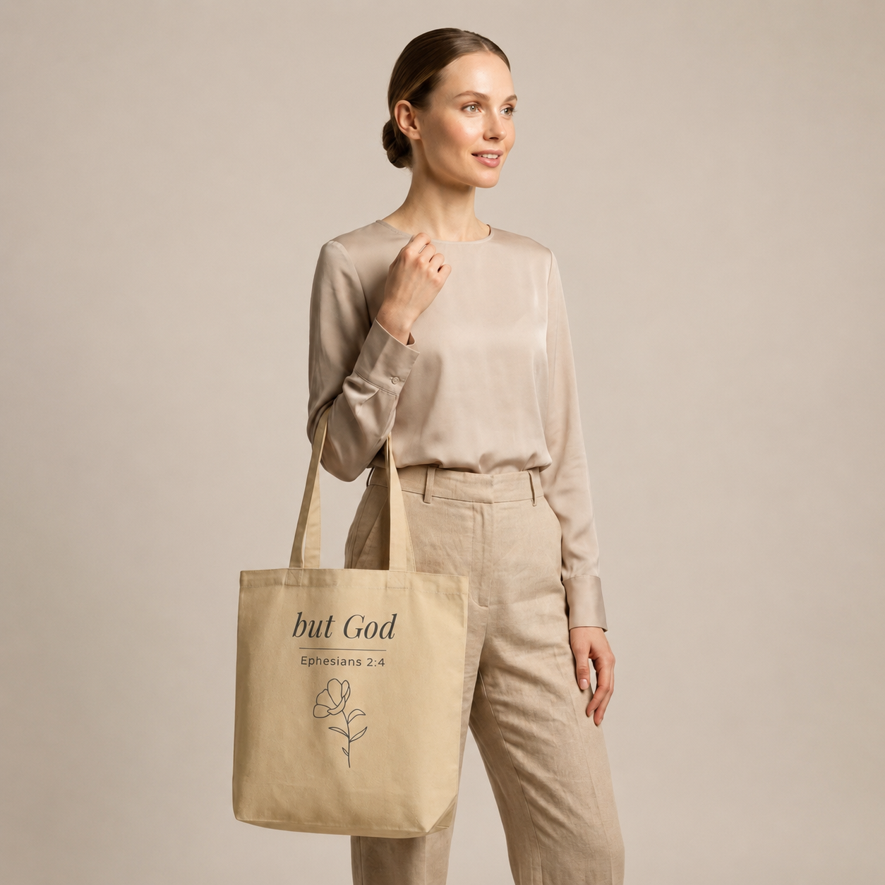 Model carrying a natural cotton Christian tote bag with beige handles and a minimalist “but God Ephesians 2:4” design.