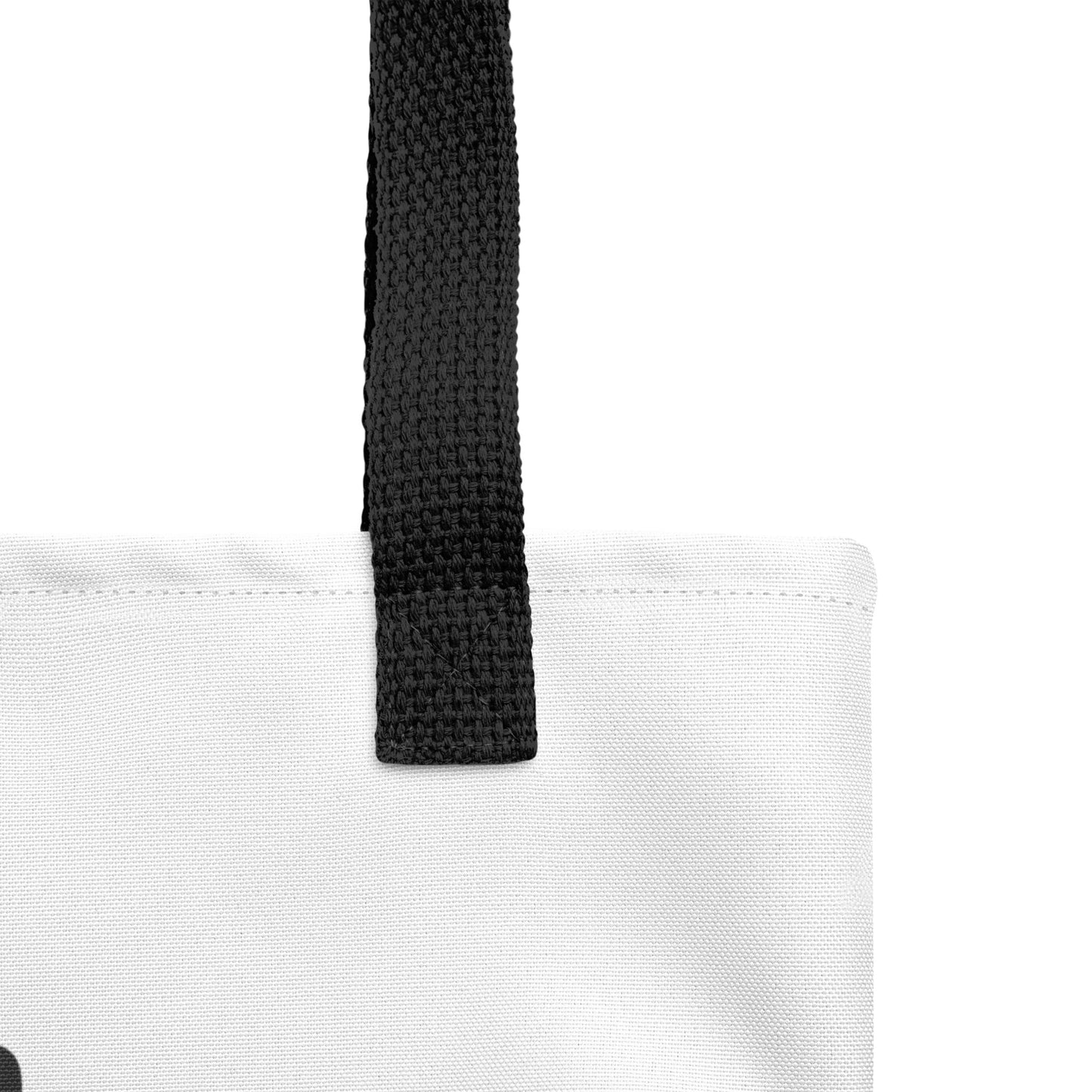 Close-up of the white tote fabric and black strap, highlighting the stitching, textured canvas, and strap weave detail.