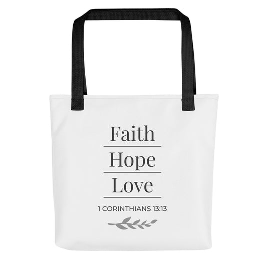 Front view of a white tote bag with black handles featuring “Faith Hope Love,” “1 Corinthians 13:13,” and a leaf design in dark gray.