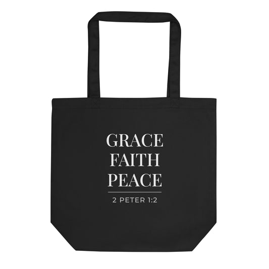 Front view of a black cotton Christian tote bag with matching black handles, featuring stacked white “Grace Faith Peace” lettering and 2 Peter 1:2 scripture text.