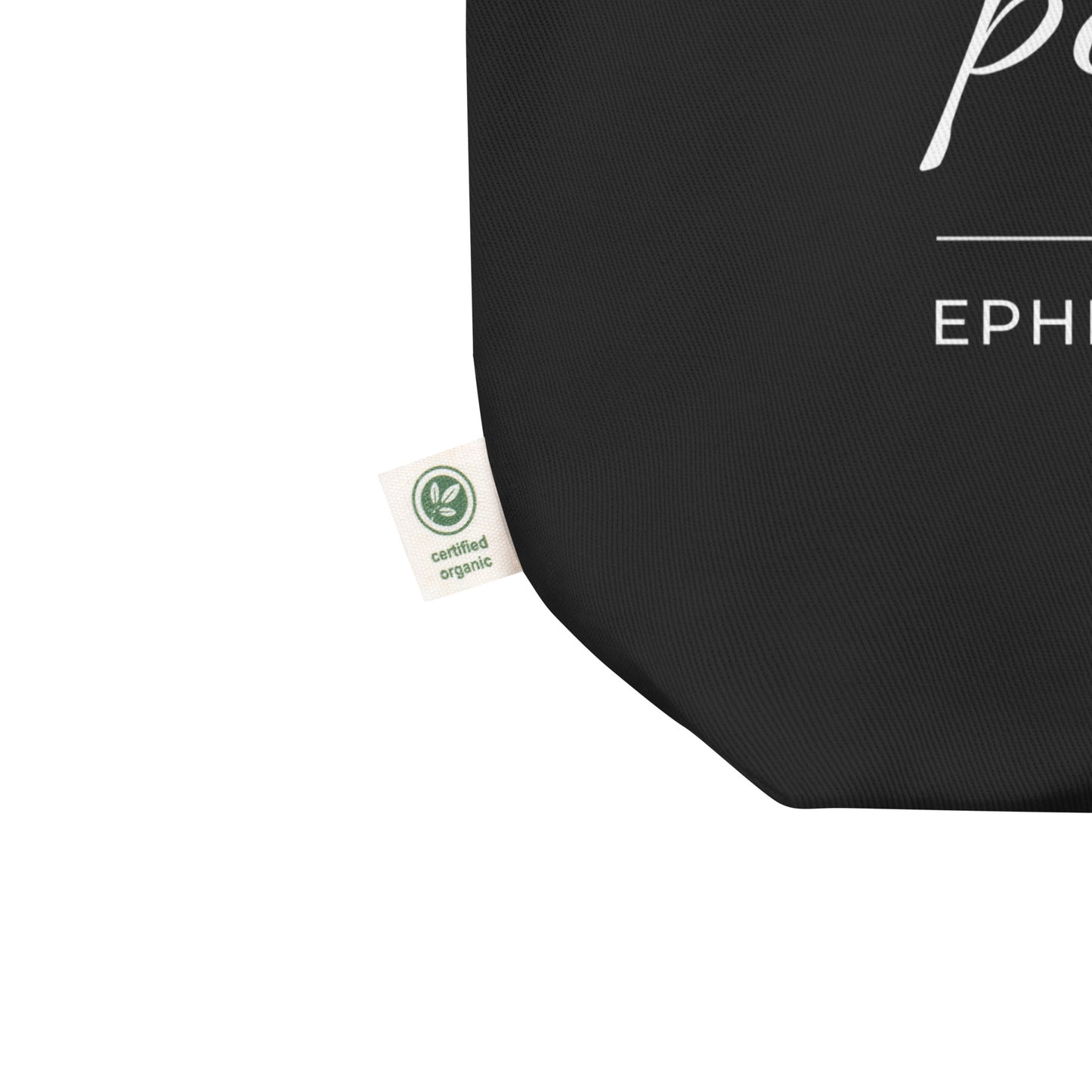 Close-up of a black cotton Christian tote bag showing the fabric texture, certified organic side tag, and part of the white “Jesus is my peace” design.