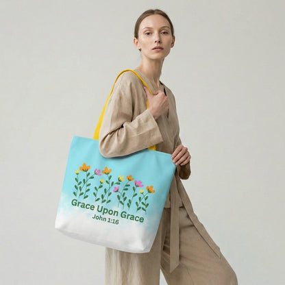 Woman holding a tote bag with floral design and 'Grace Upon Grace' text on a plain background