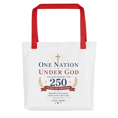 Front view of a white Christian patriotic tote bag with red handles and a “One Nation Under God 250 Years of Freedom” design.