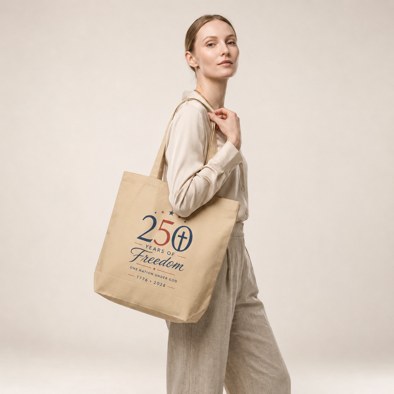 Model carrying a natural cotton Christian patriotic tote bag with a “250 Years of Freedom, One Nation Under God” design.