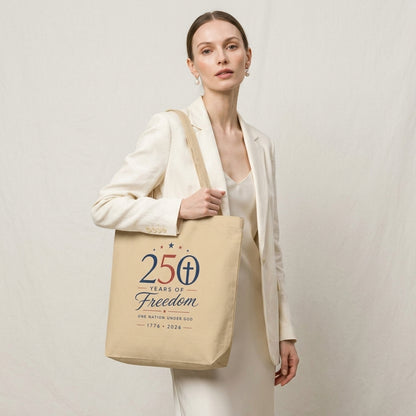 Model carrying a natural cotton Christian patriotic tote bag with a “250 Years of Freedom, One Nation Under God” design.