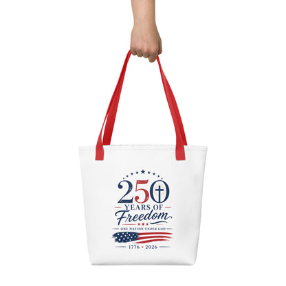Person holding a white Christian tote bag with red handles, patriotic lettering, an American flag graphic, and “One Nation Under God” text.
