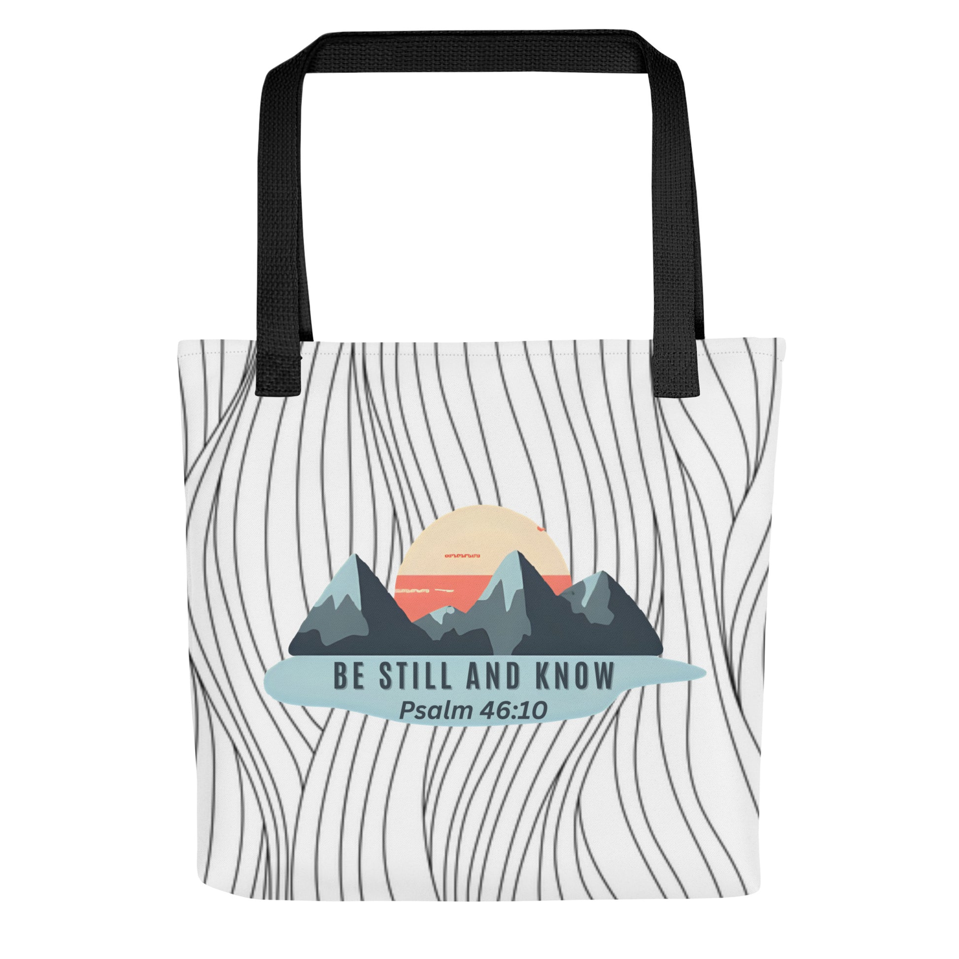 Front view of a patterned tote bag with black handles featuring a mountain-and-sun graphic and the text “BE STILL AND KNOW” with “Psalm 46:10.”