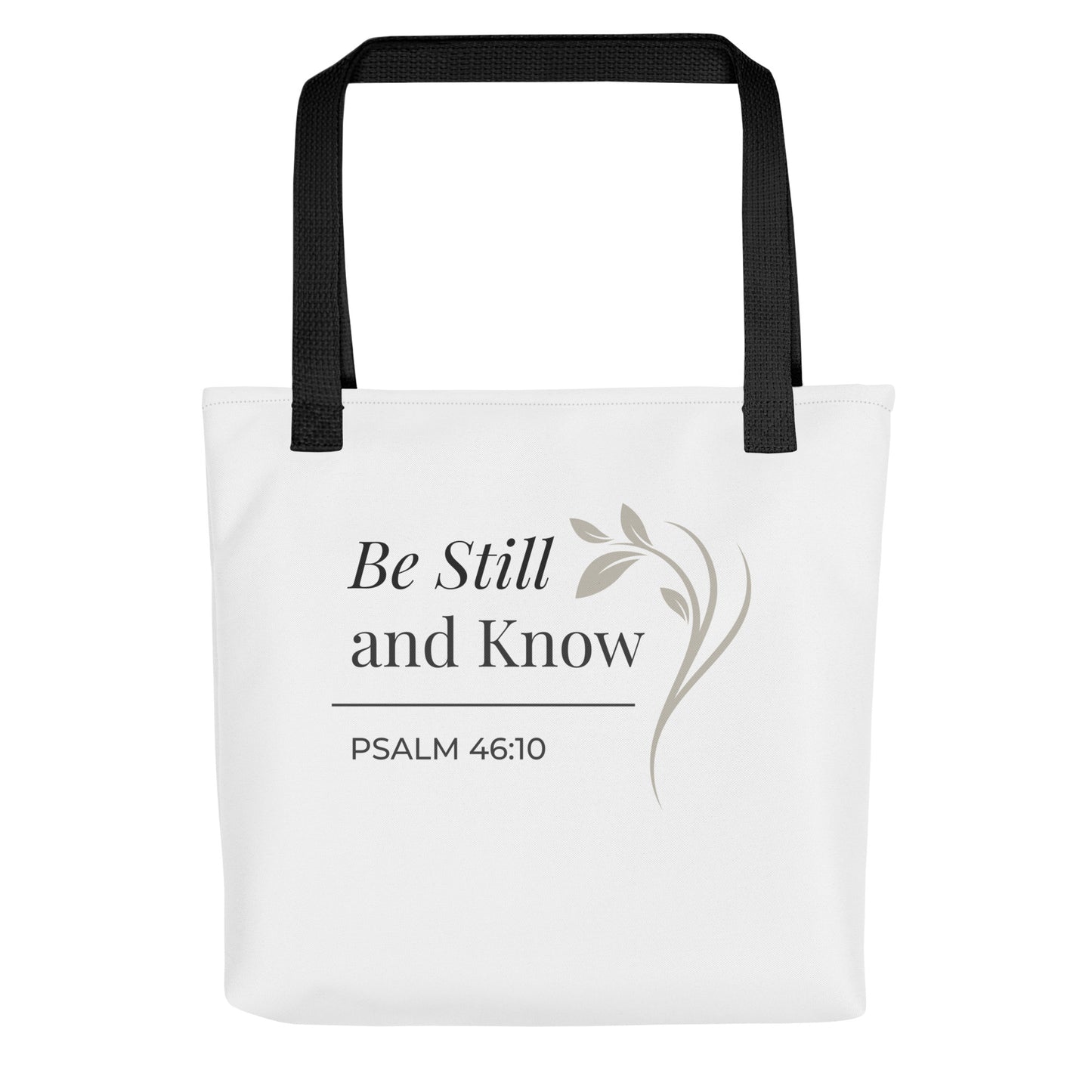 Front view of a white tote bag with black handles featuring “Be still and know,” “Psalm 46:10,” and a floral line design in dark gray.