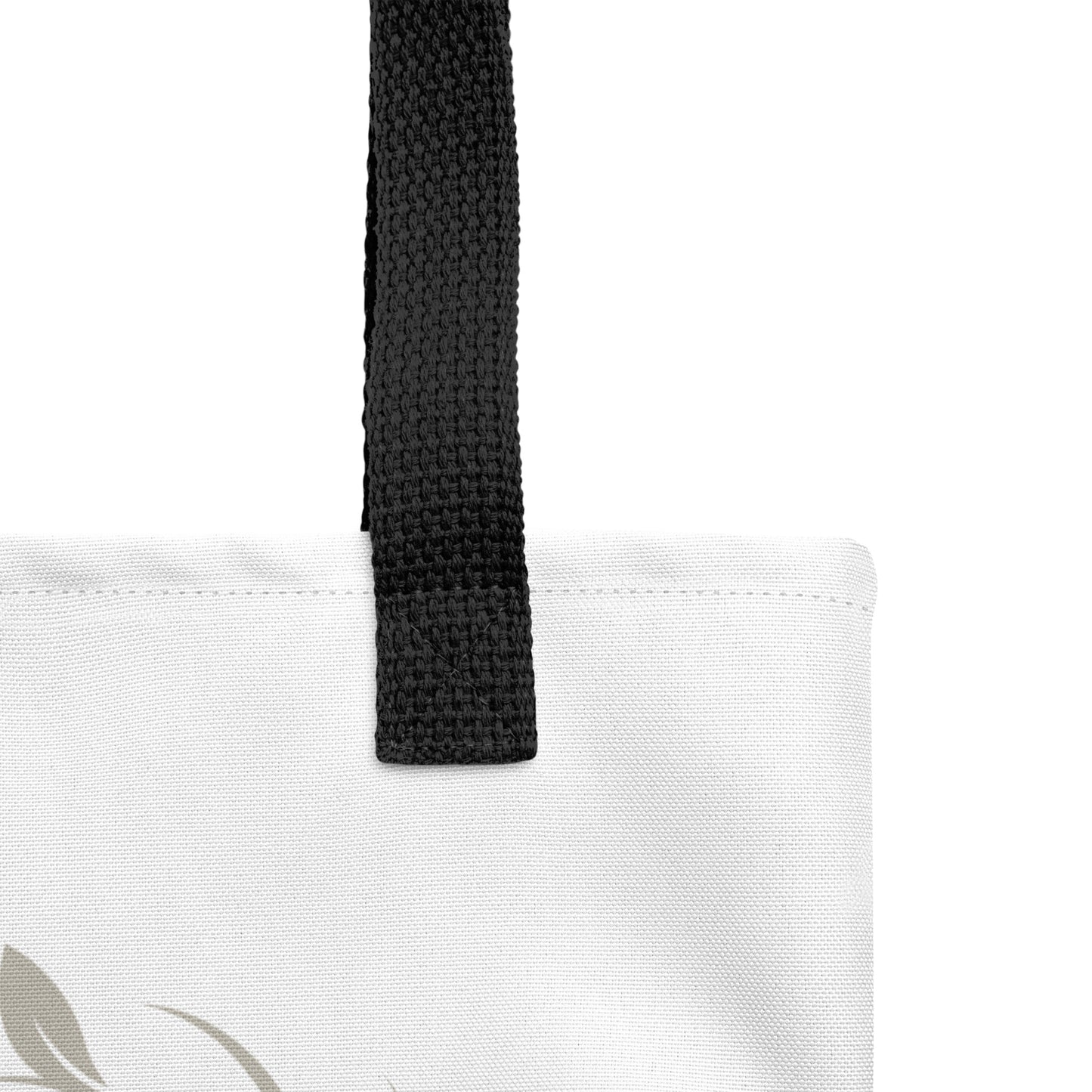 Close-up of the white tote fabric and black strap, highlighting the stitching, textured canvas, and strap weave detail.