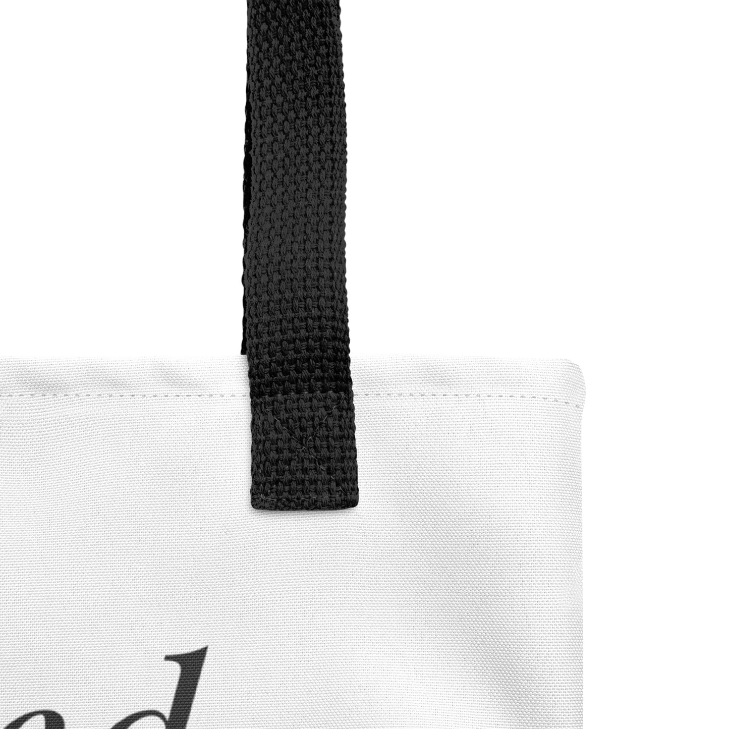 Close-up of the white tote fabric and black strap, highlighting the stitching, textured canvas, and strap weave detail.