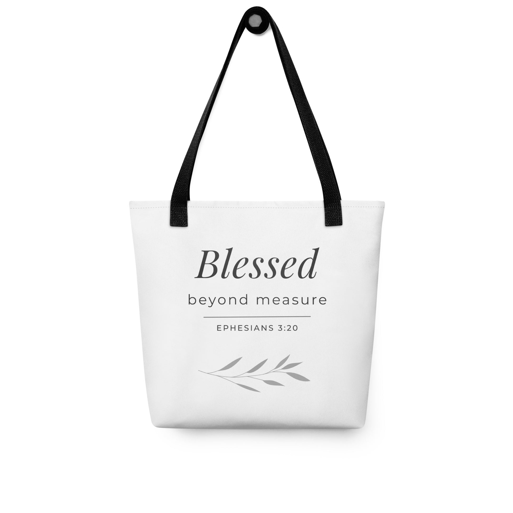 White tote bag hanging on a hook with black handles featuring “Blessed beyond measure” and “Ephesians 3:20” in dark gray with a leaf design.