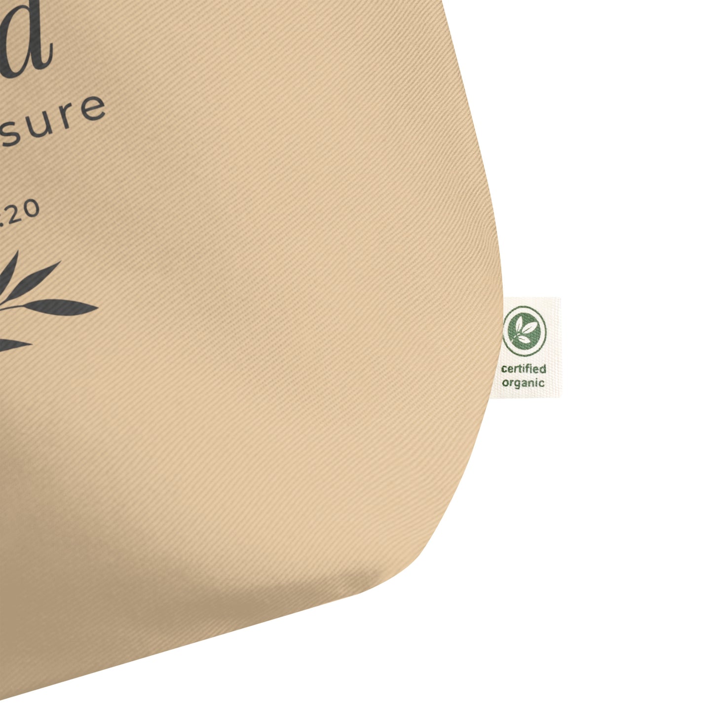 Close-up of a natural cotton Christian tote bag showing the beige fabric texture, certified organic side tag, and part of the “Blessed Beyond Measure” design.