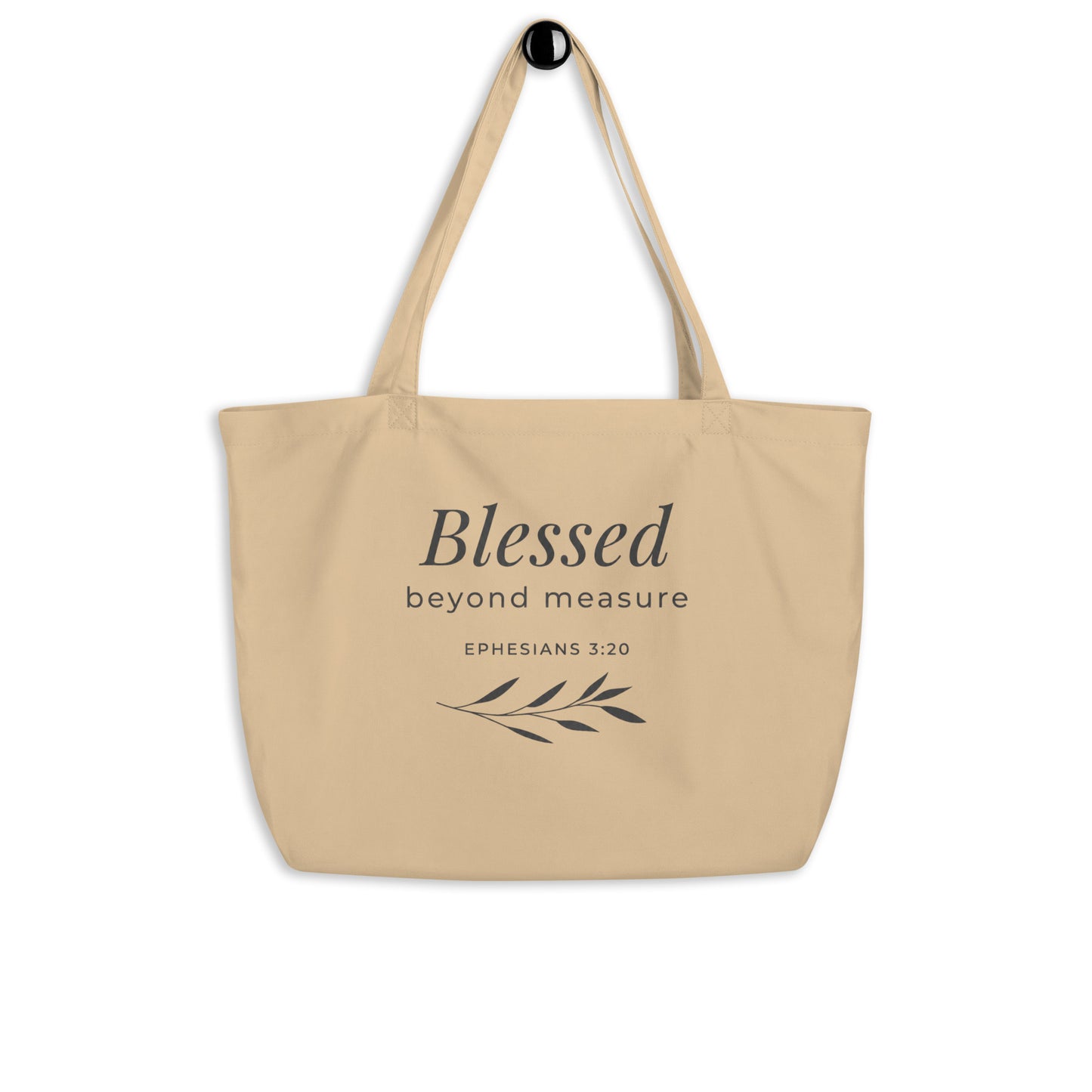 Natural cotton Christian tote bag hanging on a hook, featuring beige straps, gray lettering, and a simple “Blessed Beyond Measure” faith design.