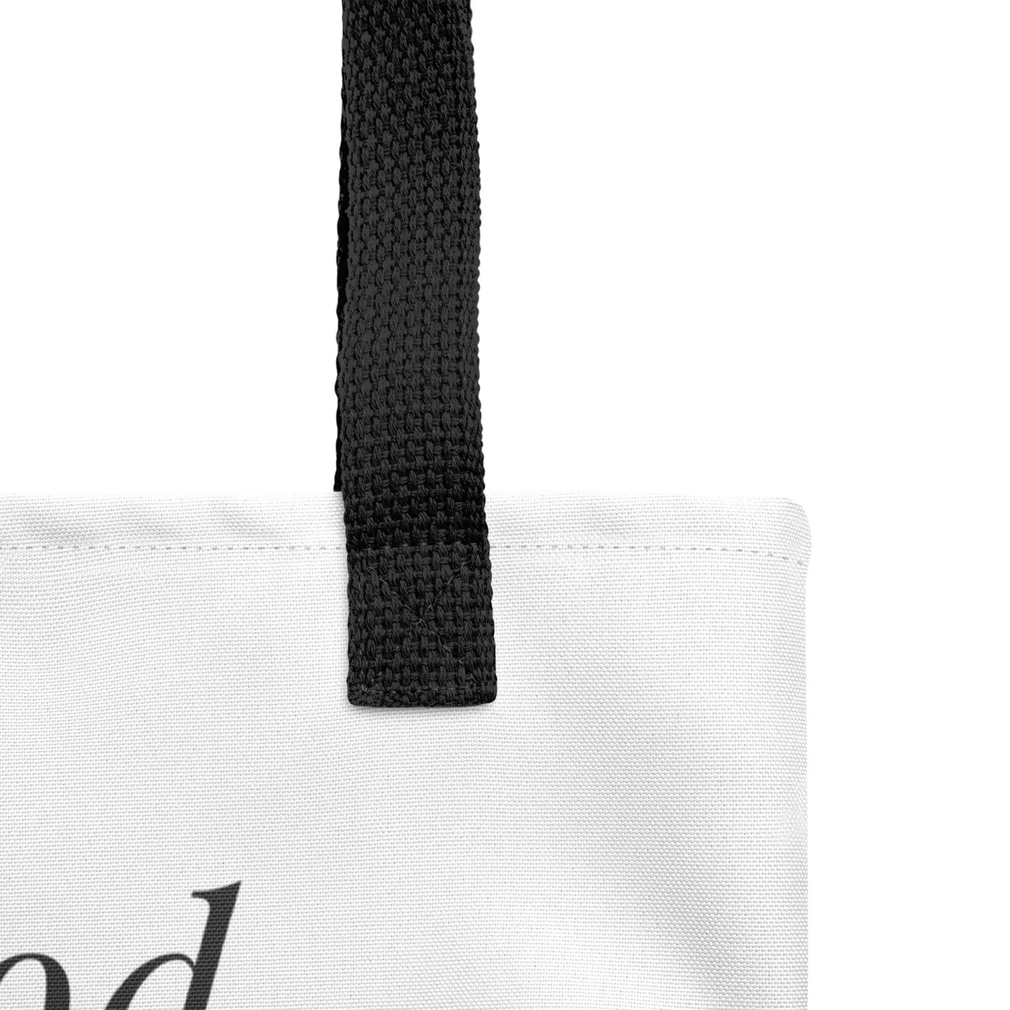 Close-up of the white tote fabric and black strap, highlighting the stitching, textured canvas, and strap weave detail.