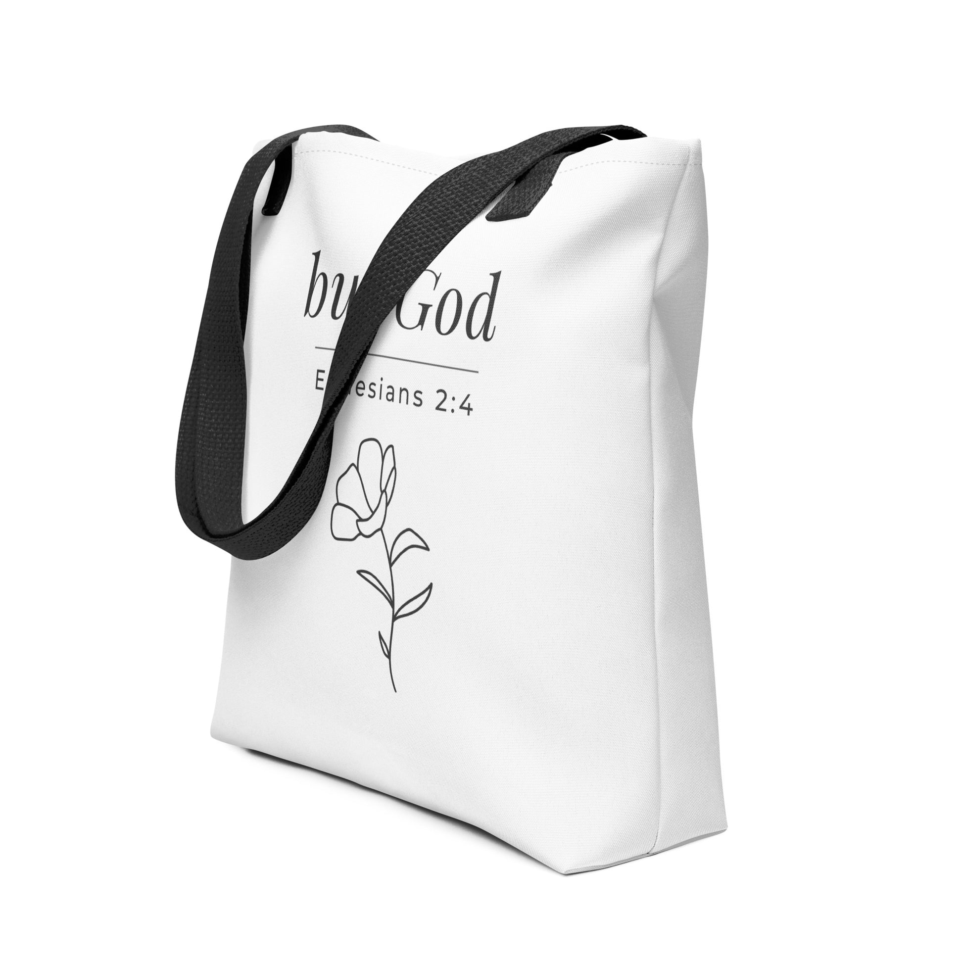 Angled view of a white tote bag with black handles featuring “but God,” “Ephesians 2:4,” and a flower line-art design in dark gray.